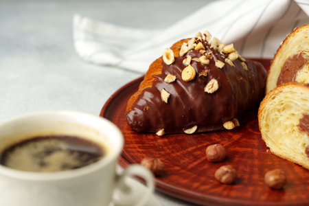 Chocolate croissant on clay plate with cup of coffee on tableの写真素材