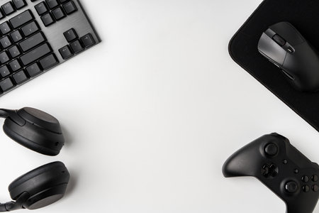 Top view of gamer table with computer keyboard, joystick and headphones