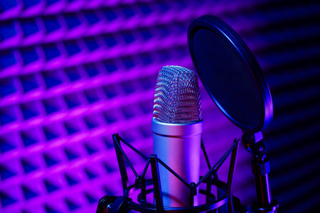 Professional studio microphone against acoustic foam panel background in neon lightの写真素材