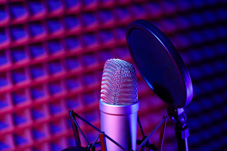 Professional studio microphone against acoustic foam panel background in neon lightの写真素材