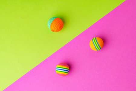 Pet toys balls on pink and green background studio shot