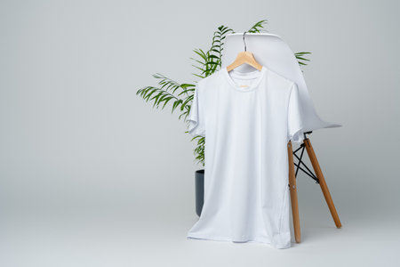 Blank white T-shirt hanging on a chair on white backgroundの写真素材