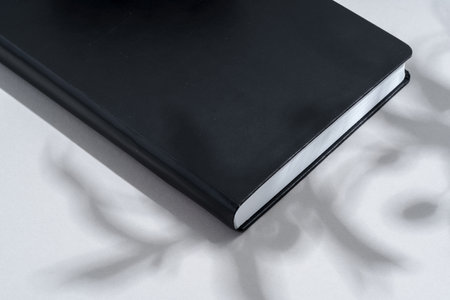 Black notepad with hard cover on gray background