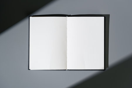 Blank open notepad on gray background studio shot