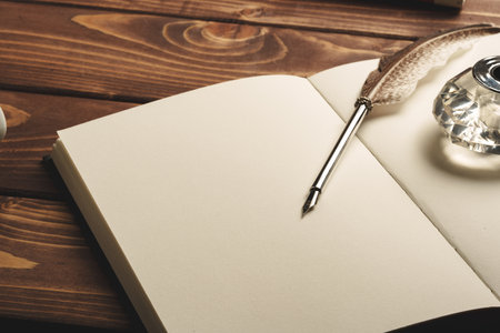 Notebook and feather pen on working table