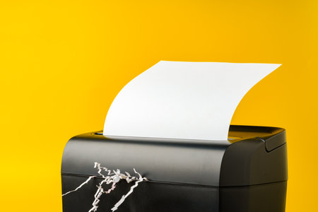 Office paper shredder on yellow studio backgroundの写真素材