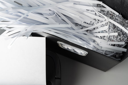 Black paper shredder cutting paper on gray backgroundの写真素材