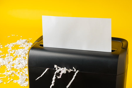Office paper shredder on yellow studio backgroundの写真素材