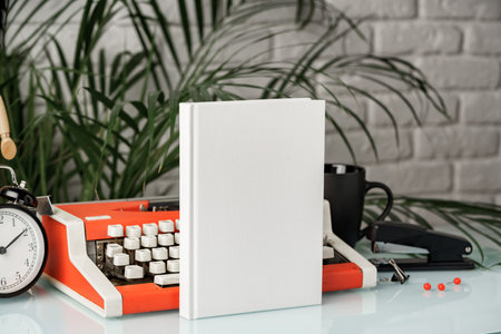 Hardcover book and vintage typewriter on white deskの写真素材