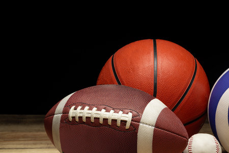 Set of various sport balls on wooden floor on black background