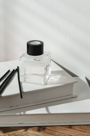 Aromatic Reed Diffuser on White Books With Shadows Playing on the Wall