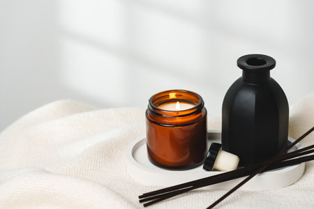 Elegant Aroma Diffuser With Reed Sticks And Scented Candle On White Tablecloth
