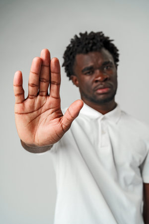 African man standing with his hand raised in the air, fingers stretched outの写真素材
