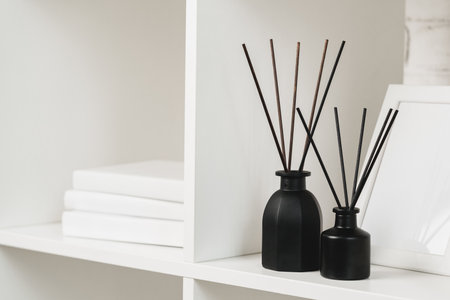 Elegant Black Reed Diffuser on White Shelf in Minimalist Home Decor Settingの写真素材