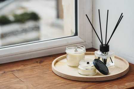 Scented Candles and Diffuser on a Wooden Tray by the Windowの写真素材