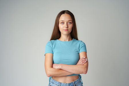 Portrait of smiling young woman in blue T-shirt on gray backgroundの写真素材