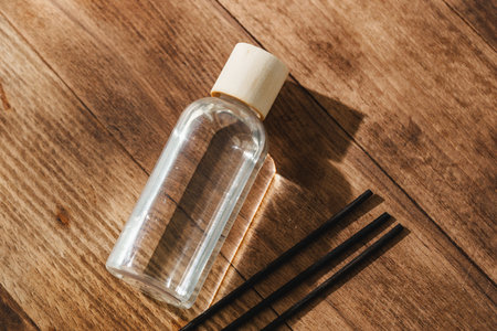 Elegant Perfume Bottle Bathed in Sunlight on a Wooden Surfaceの写真素材