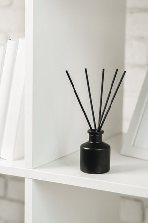 Elegant Black Reed Diffuser on White Shelf in Minimalist Home Decor Settingの写真素材