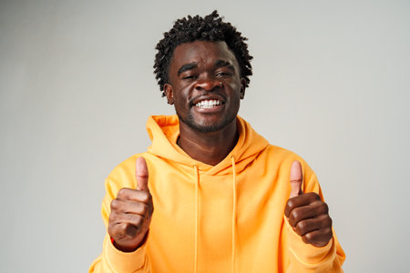 African Man in Yellow Hoodie Giving Thumbs Up studio shot