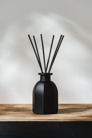 Black Reed Diffuser on a Wooden Table With Soft Light Casting Shadowsの写真素材