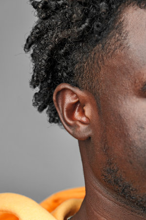 Close-Up View of African Mans Hair and Ear Against a Grey Backgroundの写真素材