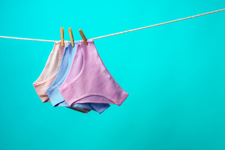 Female panties hanging on rope against blue studio backgroundの写真素材