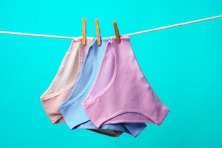Female panties hanging on rope against blue studio backgroundの写真素材