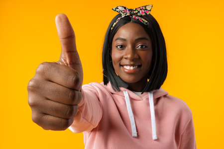African young woman over isolated yellow background with thumbs upの写真素材