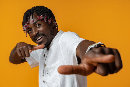 Young african man pointing to camera with fingers isolated on yellow backgroundの写真素材