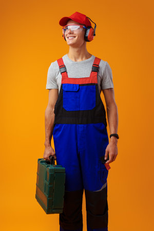 Portrait of young foreman worker with toolbox over yellow backgroundの写真素材