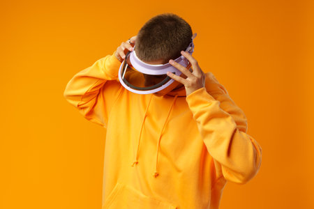 Young urban style man in sweatshirt and visor on yellow studio backgroundの写真素材