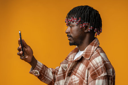 Young african man using smartphone over isolated yellow backgroundの写真素材