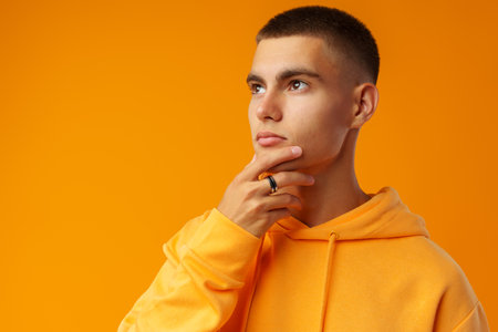 Pensive attractive young man thinking against yellow studio backgroundの写真素材