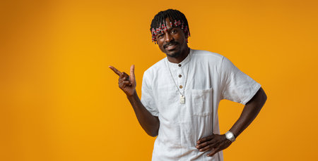 African man pointing away to side with finger over yellow background