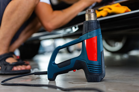 Worker applies car protection film on a car in detailing service