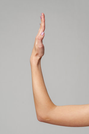 Female hand sign against gray background in studioの写真素材
