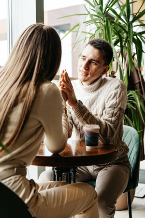 Couple Engaged in Conversation at a Cozy Cafe During Daytimeの写真素材