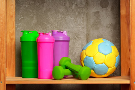 Shelves with different sports equipment against green wallの写真素材