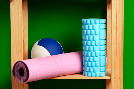 Shelves with different sports equipment against green wallの写真素材