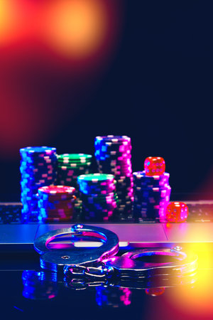 Silver Handcuffs Resting on Laptop Keyboard With Poker Chips.の写真素材