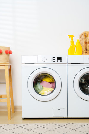 White Washing Machine With Yellow Cleaning Supplies in a Laundry Roomの写真素材