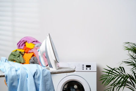 Modern Laundry Room With White Washing Machines, Ironing Board, and Houseplantの写真素材