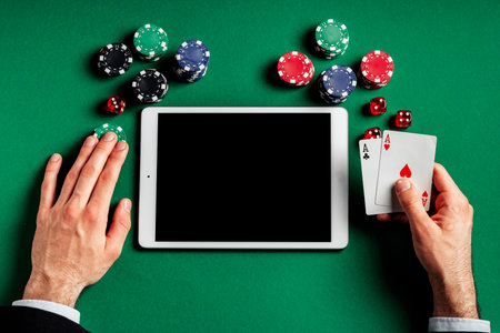 Tablet Screen With Poker Chips, Dice, and Playing Cards on Green Feltの写真素材