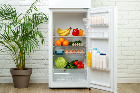 White Refrigerator Open With Fresh Produce and Dairyの写真素材