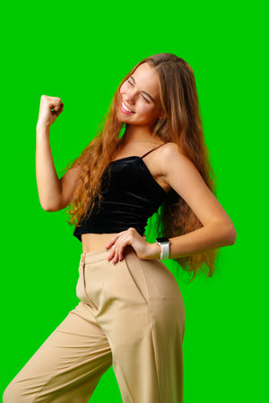 Young Woman Celebrating Success With Raised Fists Against Green Screen Backgroundの写真素材