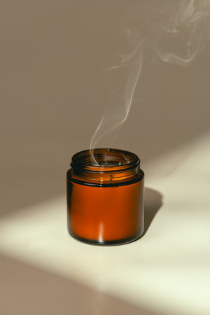 Candles in Glass Jars on a Light Beige Surfaceの写真素材