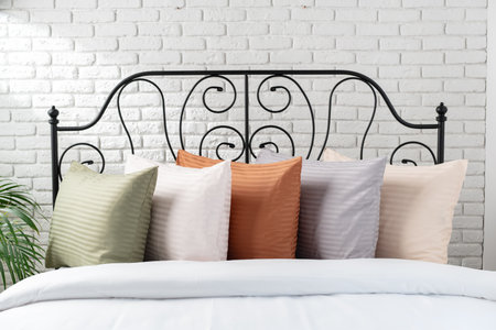 White Bed With Green Striped Pillow and Ornate Black Headboard