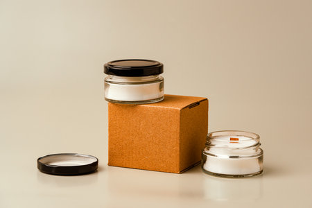 Glass Candle Jar and Cardboard Box on Beige Backgroundの写真素材