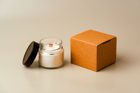 Glass Candle Jar and Cardboard Box on Beige Backgroundの写真素材
