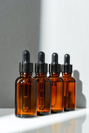 Four Amber Glass Bottles With Dropper Tops on White Surfaceの写真素材